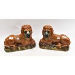 A large pair of 19th Century Staffordshire recumbent lions on plinths with glass eyes,
