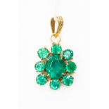 An emerald pendant set with oval cut emeralds in a flower cluster design,