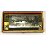 An early 20th Century harmonica in original box, embossed with makers name,