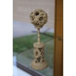 A carved Chinese ivory puzzle ball with stand, both being carved with chasing dragon,