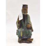 A Chinese Ming Dynasty style pottery figure of a seated elder, holding a pomegranite, 19cm high.