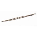 A large white metal and diamond bar brooch,