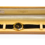 A Gucci Gents wristwatch, gold plated case, black leather strap, complete with presentation box,