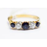 A sapphire and diamond five-stone 18ct gold ring, the central round-cut sapphire approx. 4.