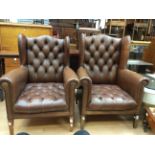 An early 20th Century brown leather upholstered wing back armchairs, deep buttoned backs and seats,