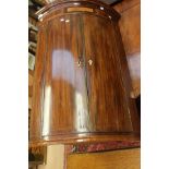 A George III mahogany bow fronted hanging corner cupboard,