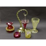 A vaseline glass arched posy holder, holding a cranberry posy bowl, with a vaseline glass vase,