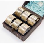 A set of six cased white metal foliate patterned napkin rings,