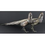 A pair of white metal peacocks, fashioned as standing male peafowls, with embossed and engraved