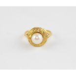 A yellow metal and cultured pearl ring, the engraved circular face set central cultured pearl, (