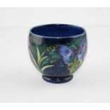 A William Moorcroft pottery bowl, tube lined with flowers and corns on a mottled blue ground,