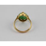 A yellow metal and mottled green jade ring, set oval cabochon jade, shank indistinctly marked, (