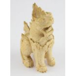 A Thai carved  ivory Fo Temple dog,realistically carved in typical pose, 15 cm high