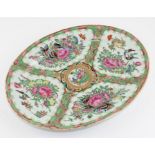 A Chinese Cantonese export oval platter in famille rose palette painted with flowers and