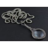 A silver, marcasite and garnet magnifying glass, the circular magnifying glass mount having one side