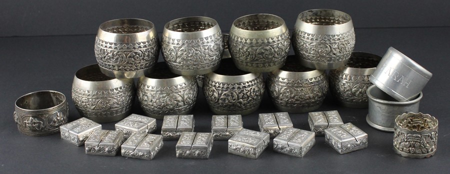 A set of twelve Cambodian silver place name/menu holders, of square form, repousse decorated flowers