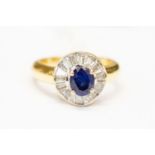 A sapphire and diamond set ring, central claw set oval sapphire with tapered baguette cut surround,