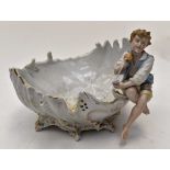 A German porcelain shell shaped dish with a boy holding fruits sitting on the rim,