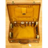 A gentleman's leather case containing silver topped faceted glass toiletry bottles,