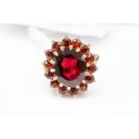 A 9ct gold ring with a large garnet stone, surrounded by smaller stones,