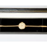 A Cyma 9ct gold ladies watch, round dial, approx 18mm, on a 9ct gold strap, length approx 18cm,