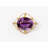 An amethyst and seed pearl brooch, oval amethyst set to the centre with 15 ct gold openwork detail,