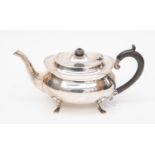 A George V silver oval shaped teapot, on four shell and hoof feet,