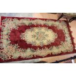 A Chinese red ground woollen rug, with cream floral decoration,