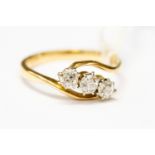 A diamond and 18ct gold ring, the three round brilliant cut diamonds set in a cross over design,