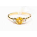 A yellow sapphire and diamond three stone ring,