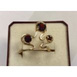 A stylised Bernard Instone 9ct gold and garnets ring, wave form to the top with three claw set round