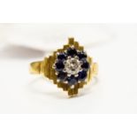 A diamond and sapphire cluster ring, set with a central brilliant cut diamond,