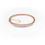 A late Victorian / early Edwardian 9ct rose gold bracelet, claw set graduated oval opals, hinged,