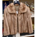 A short honey coloured mink jacket with ¾ sleeves,