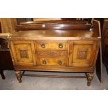 An early 20th Century oak and burr walnut veneered sideboard, raised on cup and cover legs,
