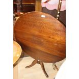 A mid 19th Century oak circular tilt top tripod table, turned column, raised on three sabre legs,