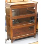 An early 20th Century oak three tier stacking bookcase, the glazed doors opening and sliding back,