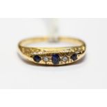An 18ct gold, diamond and sapphire ring, scroll engraved shoulders, size N1/2,