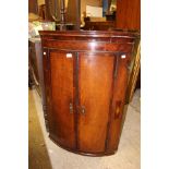 A George III oak bow fronted hanging corner cupboard,