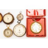 A travel clock along with a silver pocket watch and pocket barometers