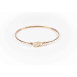 An unmarked 9ct gold bangle, open stylized circular detail to the top,