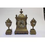 A late 19th Century brass clock garniture with porcelain inserts,