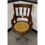 A French Edwardian swivel chair with pull out Bergere seat on cast iron stand with lion headed feet