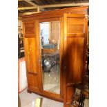 An Edwardian mahogany triple sectioned wardrobe, fitted with three doors,