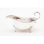 A silver sauce boat, bead rim and scroll handle,