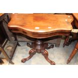 A mahogany shaped folding card table on a pedestal base with quadruped scrolled feet,