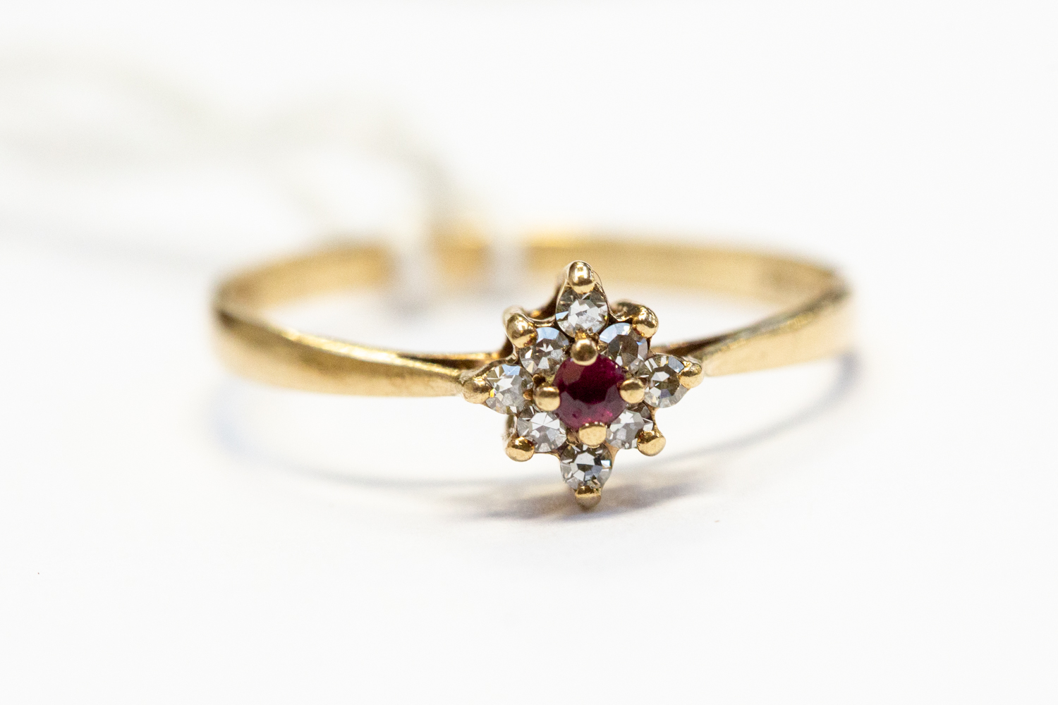 A ruby and diamond set cluster ring, round cut ruby to the centre with a claw set diamond surround,