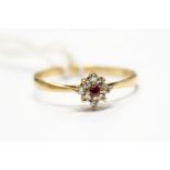 A ruby and diamond set cluster ring, round cut ruby to the centre with a claw set diamond surround,