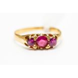 A ruby set dress ring, three graduated claw set round rubies set to the front, size L,