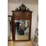 An early 20th Century veneered mirror with cherub finial,